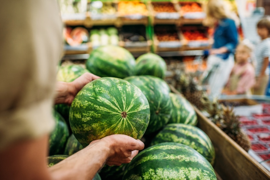 partial view of woman picking watermelon in grocery shop