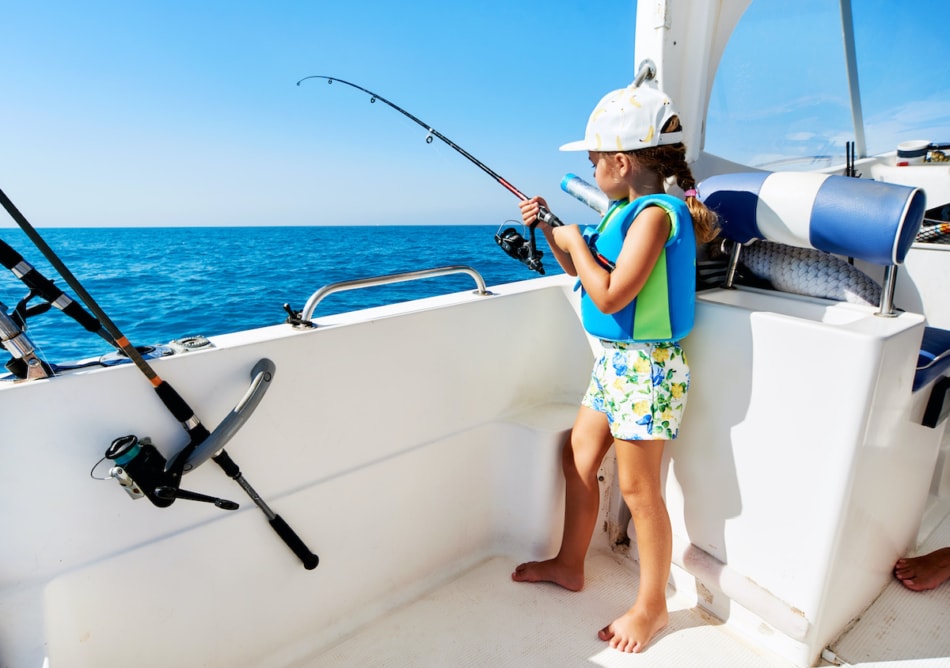 little girl with a fishing rod fishing from the boat