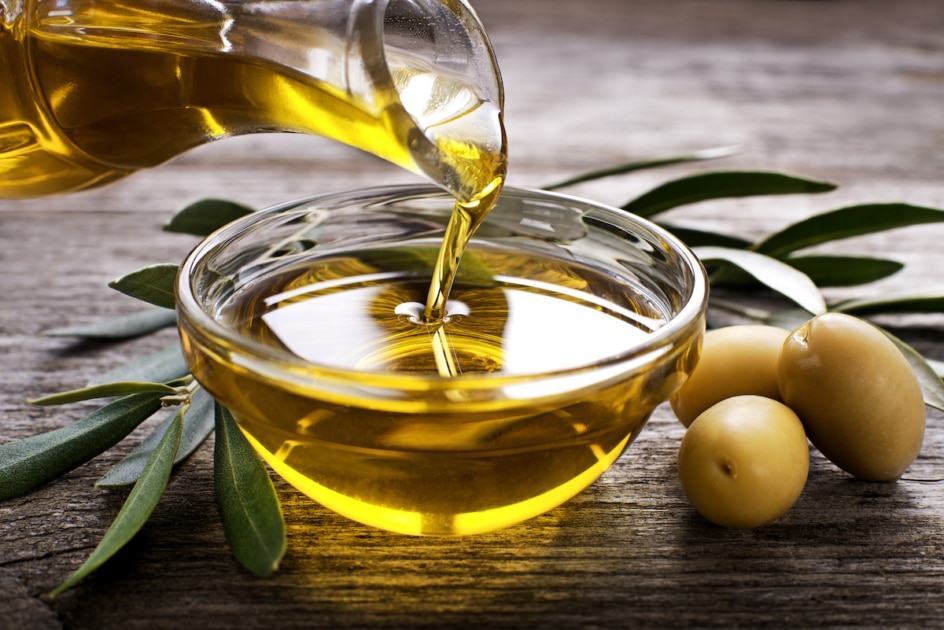 Bottle pouring virgin olive oil in a bowl close up.