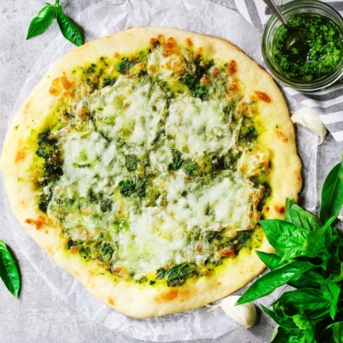 Homemade Pesto Pizza with white sauce overhead view.