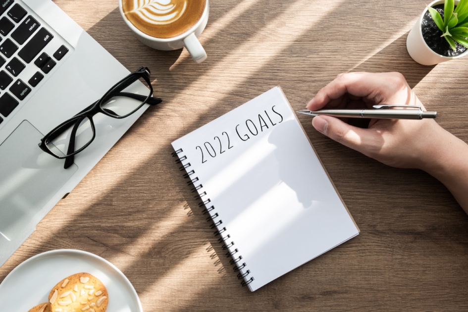 Man is writing 2022 goals for new year resolutions plan.