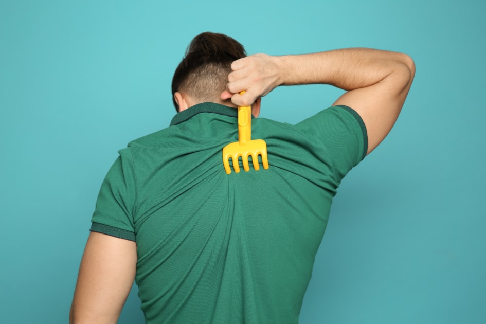 A man scratching his back with a backscratcher.