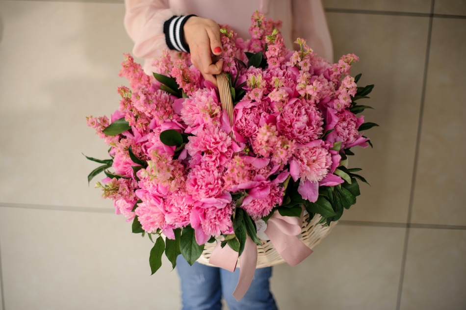 Girl holding a beautiful basket of pink peonies