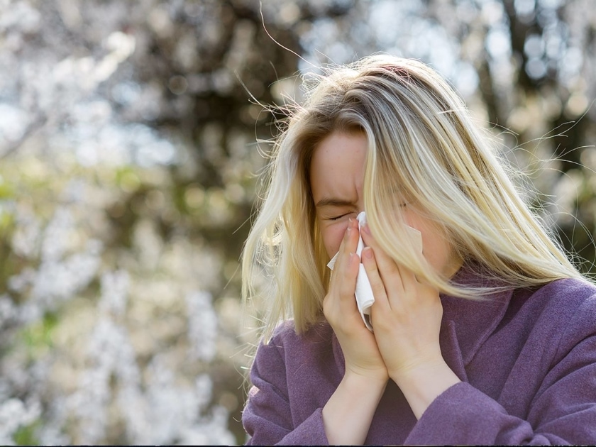 A woman with spring allergies sneezing.