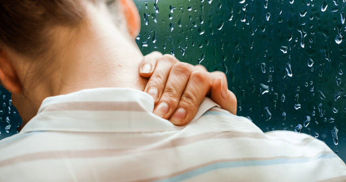 woman rubbing shoulders with rainstorm
