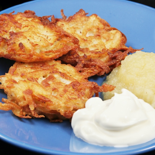 Potato latkes for Hanukkah, served with sour cream and applesauce .