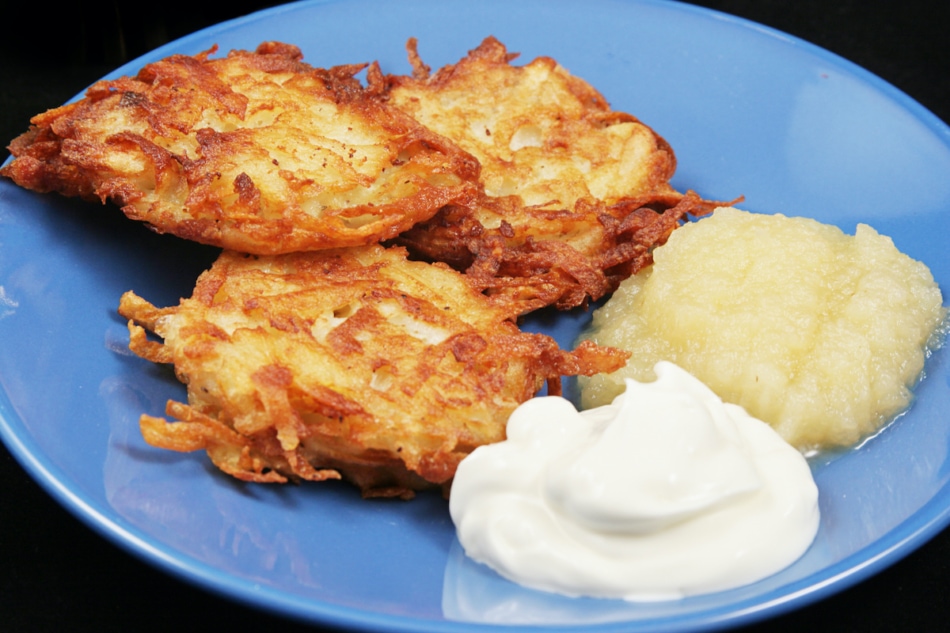 Potato latkes for Hanukkah, served with sour cream and applesauce .