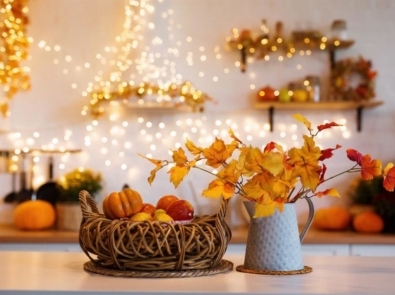 Autumn kitchen interior. Red and yellow leaves and flowers in the vase and pumpkin on light background.