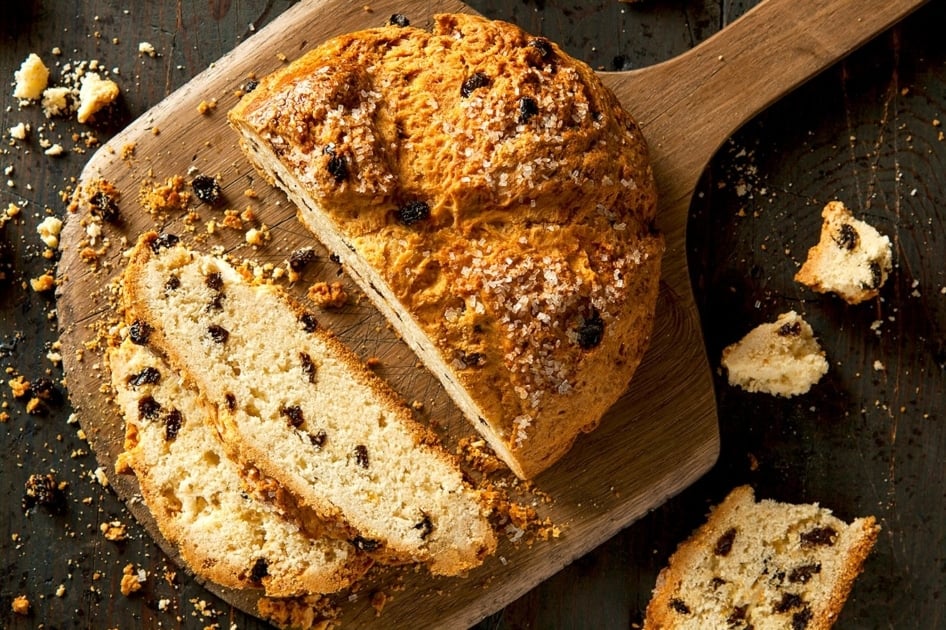 A beautiful loaf of Irish soda bread cut on a cutting board.