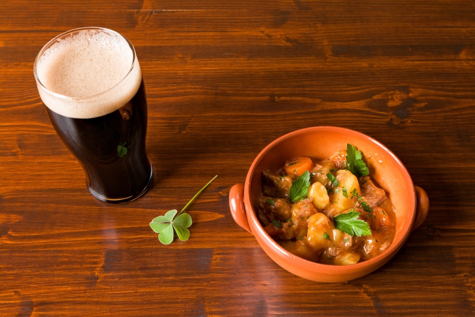 Traditional Irish Stew with a pint of stout beer and a shamrock.