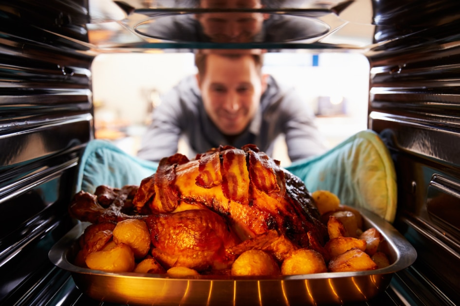 Man Taking Roast Turkey Out Of The Oven.