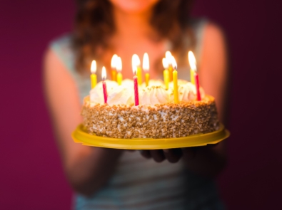 Hands of young woman holding birthday cake selective focus.
