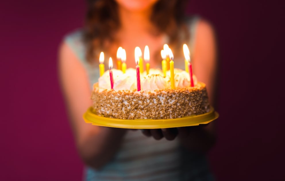 Hands of young woman holding birthday cake selective focus.