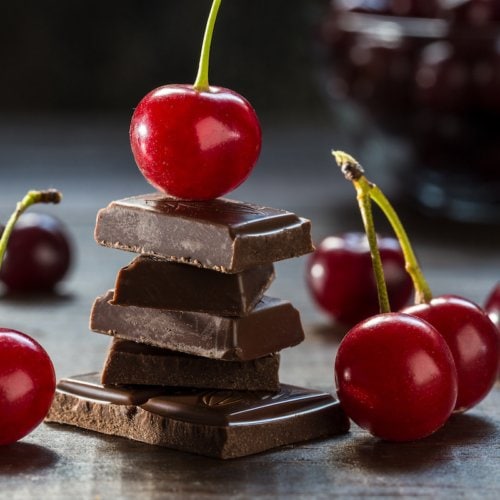 Cherries and broken chocolate on a dark background.