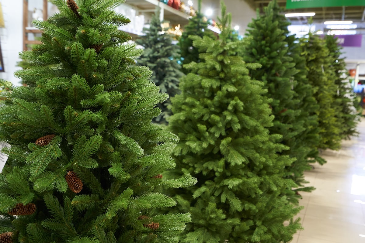 Rows of green artificial Christmas trees on display in a department store pavilion.
