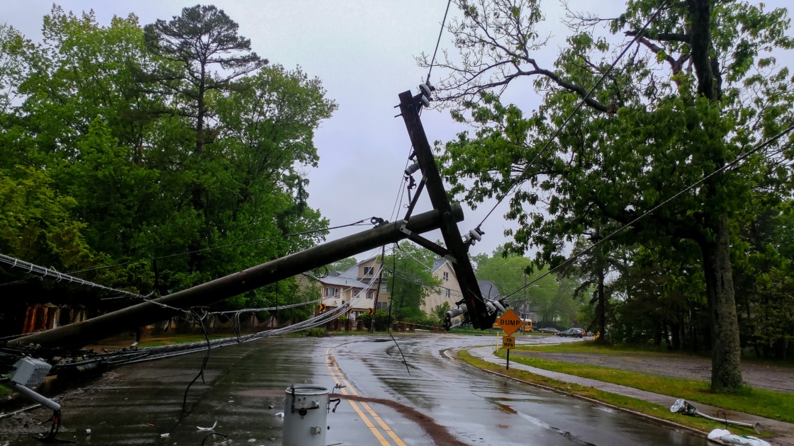 An electric post collapsed on the street and power lines down due to a storm.