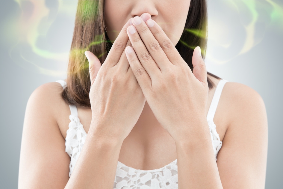 woman with bad breath covering her mouth