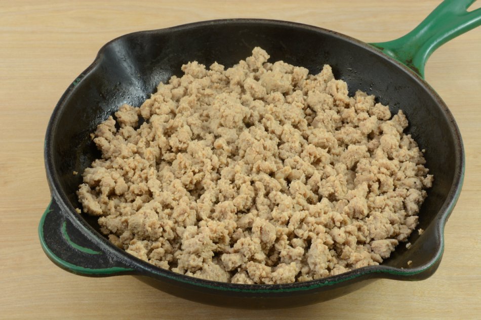 Cooked ground turkey meat in cast iron frying pan.