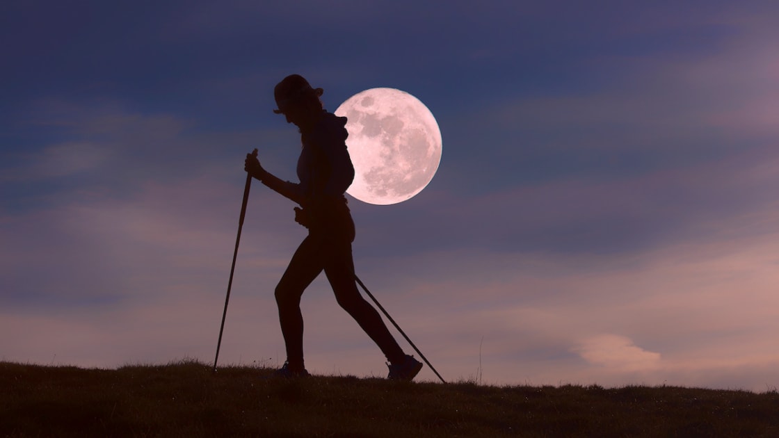 Person walking in front of full moon.