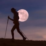 Person walking in front of full moon.