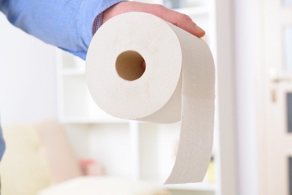 Hand holding toilet paper.
