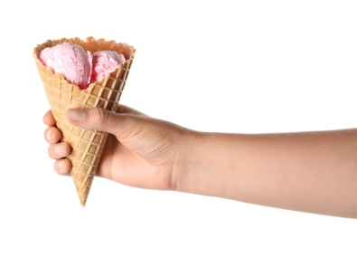 Woman holding delicious ice cream in wafer cone on white background, closeup
