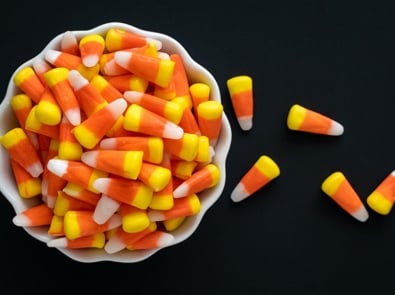 Candy corn overflowing from a white bowl.