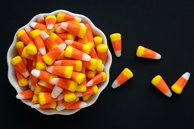 Candy corn overflowing from a white bowl.