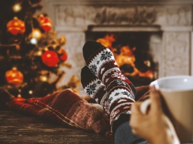 Woman legs with Christmas socks and fireplace.