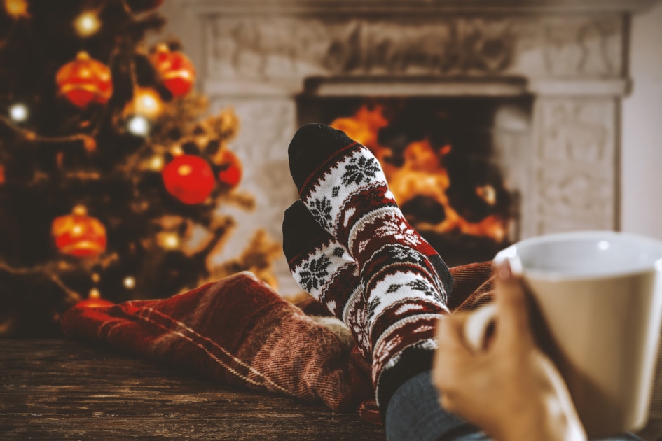 Woman legs with Christmas socks and fireplace.