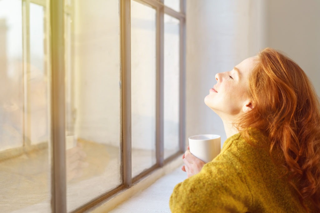 woman soaking in the sun from window on a winter day