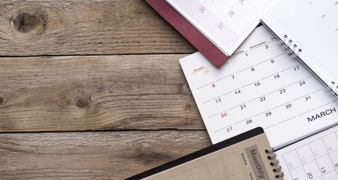 Variety of calendars spread on a wooden table as seen from above.