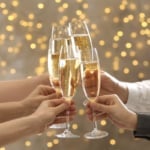 People clinking glasses of champagne on blurred background.