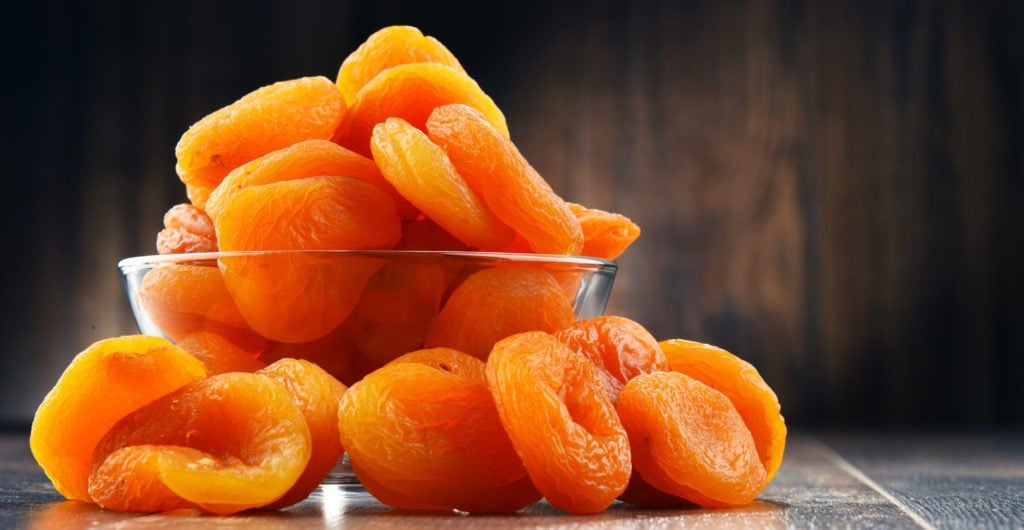 Bowl with dried apricots on wooden table