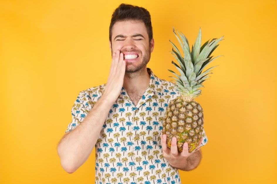 Young caucasian man with short hair wearing red shirt standing over isolated yellow background touching mouth with hand with painful mouth sore