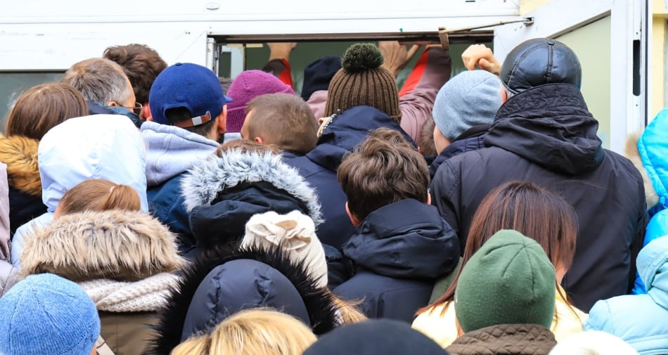 menigte van mensen in de winter kleding proberen te zwembad in een kleine ingang tijdens Black Friday.