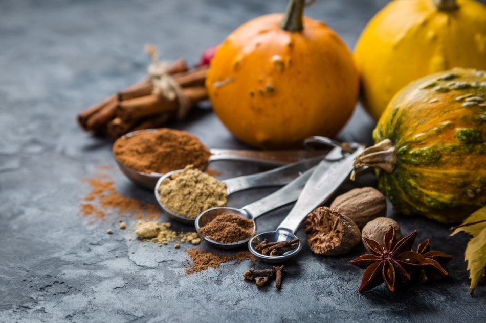 Pumpkin pie spices in measuring cups, rustic background