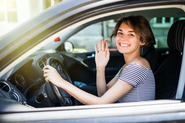 young woman in striped shirt waving from a car in a Mother's Day car parade