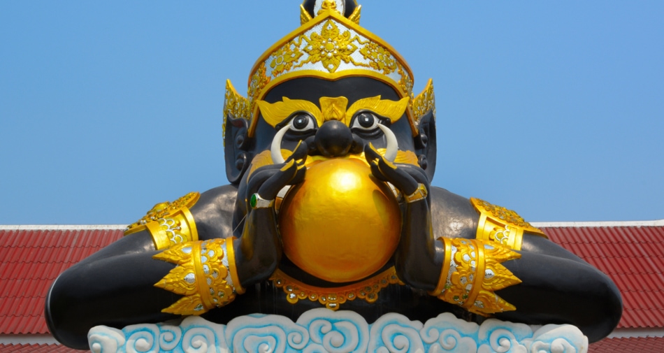 A statue of Rahu the hungry demon holding a golden globe that depicts the sun.