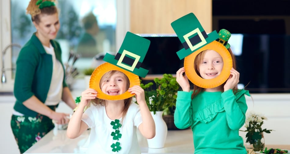 Two girls with their mom creating St Patrick's Day crafts.