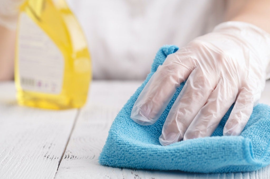 Hand in a protective glove with a washing sponge and spray sprinkle