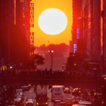 Sun appearing over city block in New York City, known as Manhattanhenge (Manhattan henge).