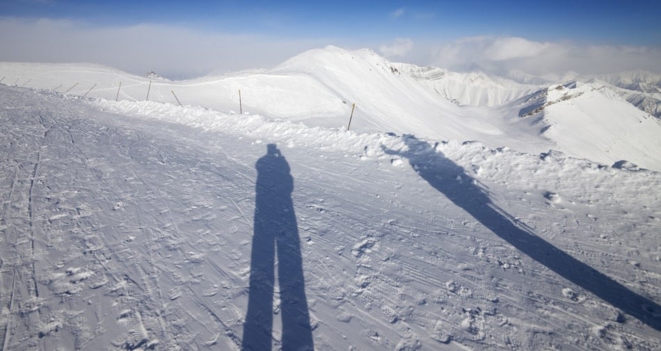 Shadow of several figures taking pictures of the snow.