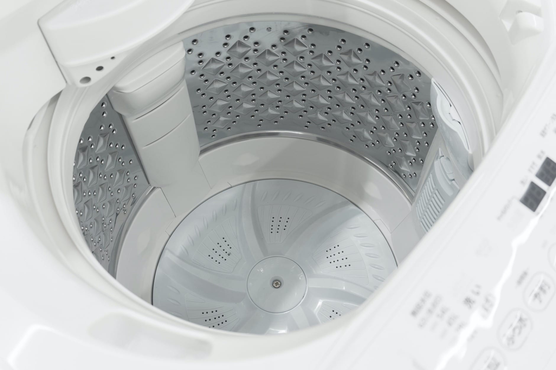 An open top-loading washing machine being cleaned.