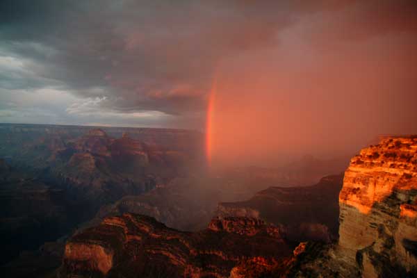 A rainbow appears at Grand Canyon during a setting sunset.