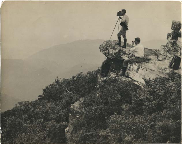 Black and white old photograph of George Masa photographing the Great Smoky Mountains.