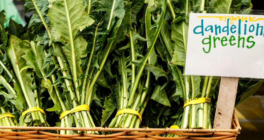 dandelion greens sign with dandelion greens in a basket