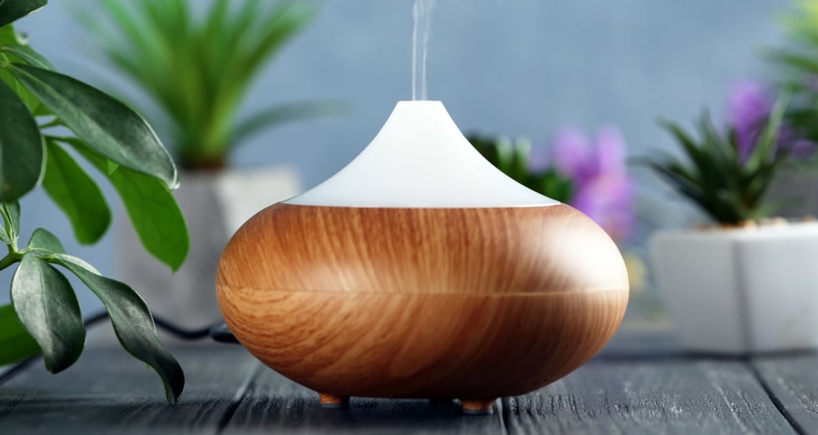 An oval shaped diffused essential oils disperser with a wooden cover.