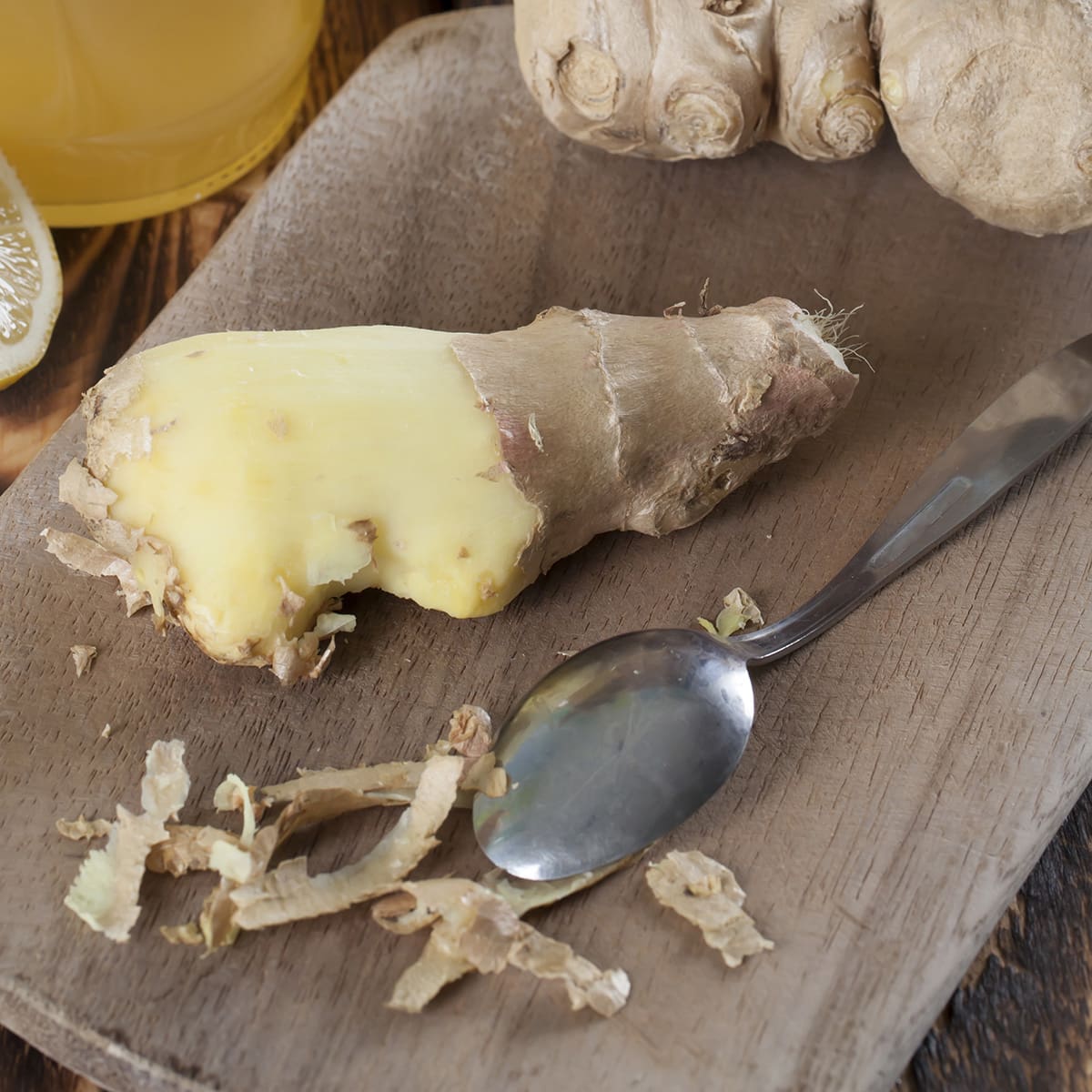 Spoon on cutting board with fresh ginger.