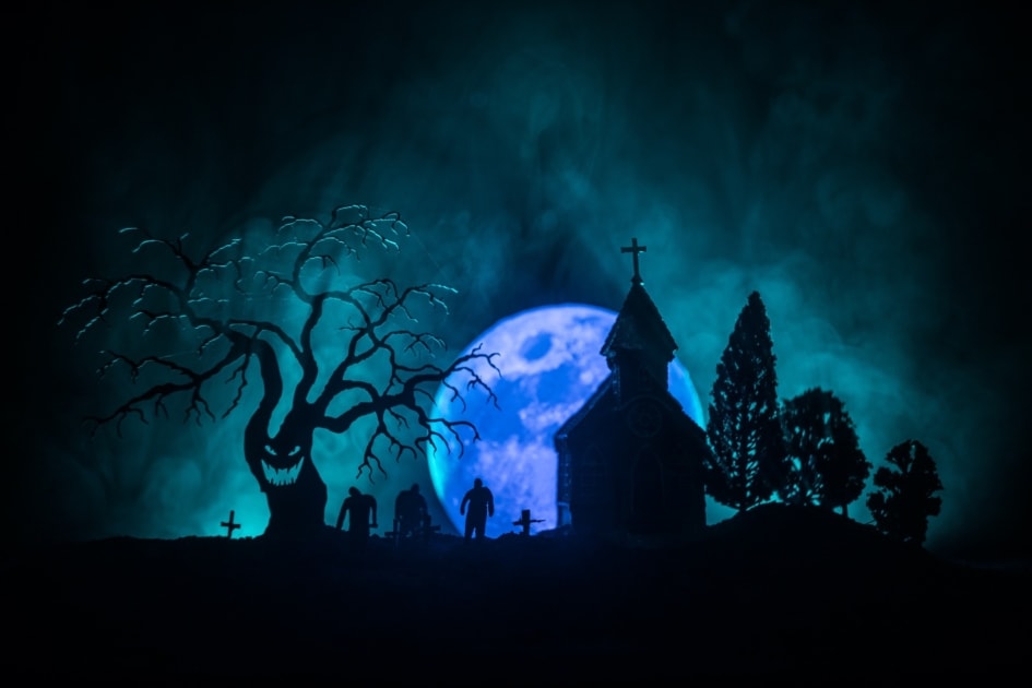 Blue full moon appearing over a graveyard with zombies in the background.